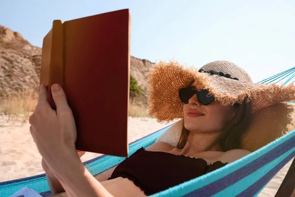 Młoda kobieta czytanie książki w hamaku na plaży — Zdjęcie stockowe