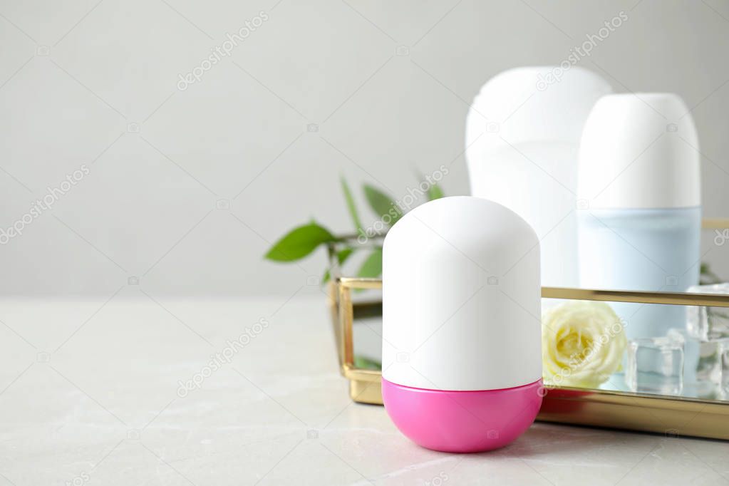 Female roll-on deodorants on white wooden table against grey background, space for text