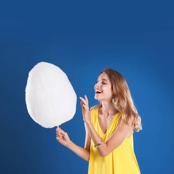 Mujer joven feliz con algodón de azúcar sobre fondo azul — Foto de Stock