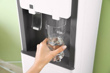 İç mekanlardaki su soğutucusu camLarını dolduran kadın, yakın çekim. Ferahlatıcı içecek