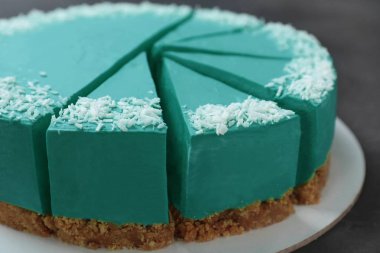 Koyu gri masa üzerinde dilimlenmiş lezzetli spirulina cheesecake, closeup görünümü