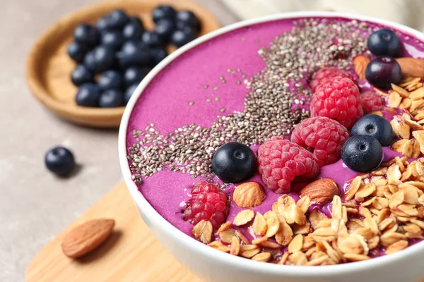 Delicious acai smoothie with berries and granola in bowl on table, closeup — Stock Photo, Image