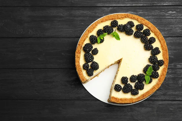 Delicious cheesecake decorated with blackberries on blue wooden table, top view. Space for text