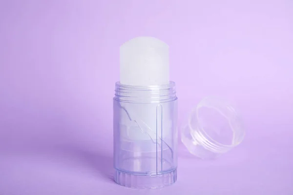 Desodorante y tapa de palo de alumbre de cristal natural sobre fondo lila —  Fotos de Stock