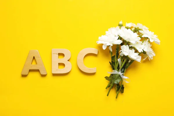 Flat lay composition with flowers and letters on yellow background. Teacher's day