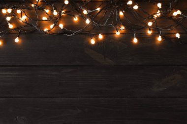 Koyu ahşap arka plan üzerinde Parlayan Noel ışıkları, üst görünümü. Metin için alan