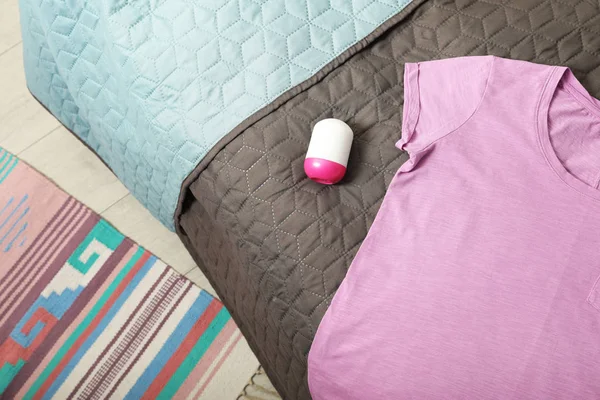 Жіноча футболка з дезодорантом та бузковою футболкою на ліжку, вид зверху. Простір для тексту — стокове фото