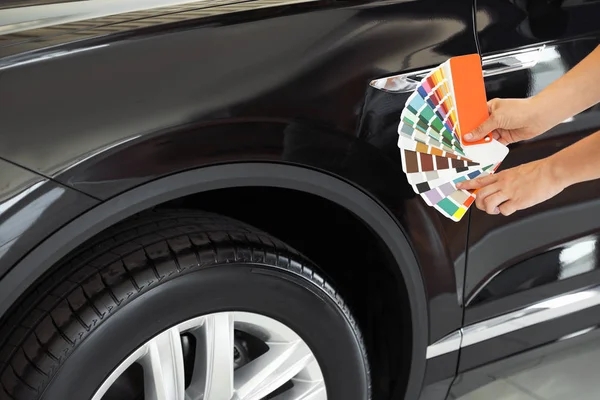 Jonge vrouw Holding palet met kleurmonsters in de buurt van zwarte auto, close-up — Stockfoto