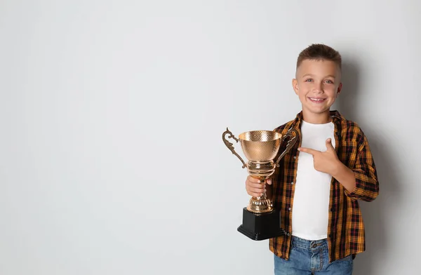 Happy Boy met gouden winnende Cup op lichte achtergrond. Ruimte voor tekst — Stockfoto