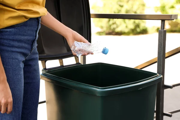 Genç kadın geri dönüşüm kutusu içine plastik şişe atma açık havada, closeup