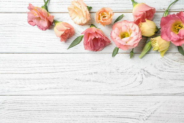 Flat lay composition with beautiful Eustoma flowers on white wooden table, space for text — Stock Photo, Image