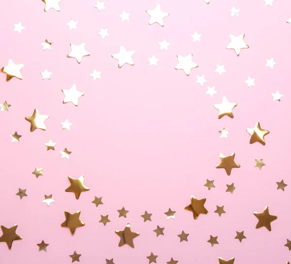 Frame made of confetti stars with space for text on pink background, top view. Christmas celebration