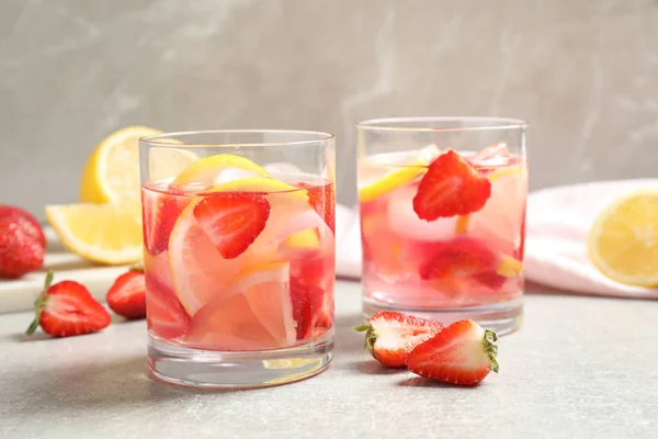 Bebida refrescante saborosa com morangos e limão na mesa cinza claro — Fotografia de Stock