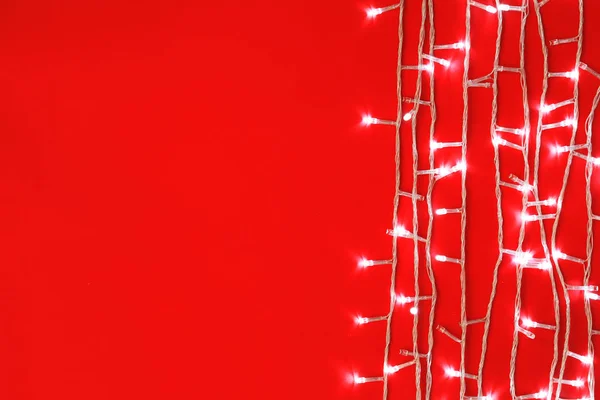 Christmas lights on red background, top view. Space for text — Stock Photo, Image