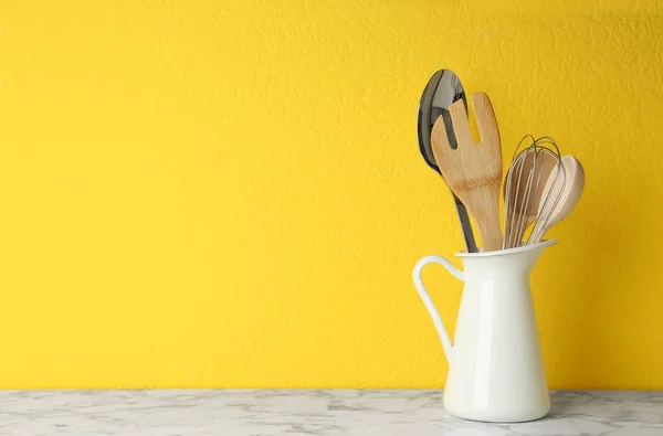 Jarra con utensilios de cocina sobre mesa de mármol sobre fondo amarillo. Espacio para texto — Foto de Stock