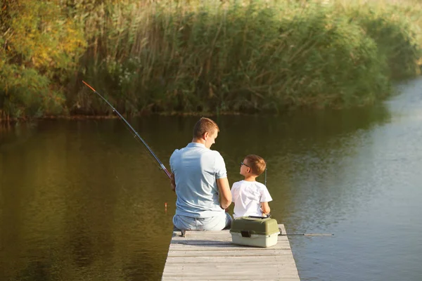 Dad and son fishing together on sunny day