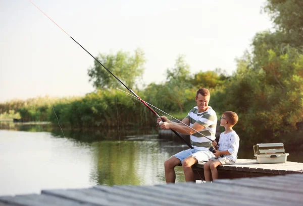 Dad and son fishing together on sunny day