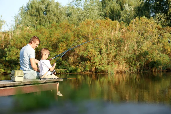 Papá e hijo pescando juntos en un día soleado. Espacio para texto — Foto de Stock