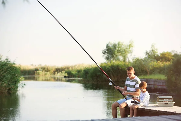 Pai e filho pesca juntos no dia ensolarado — Fotografia de Stock