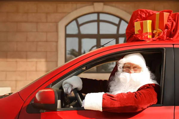 Autentico Babbo Natale con borsa piena di regali sul tetto guida auto moderne, all'aperto — Foto Stock