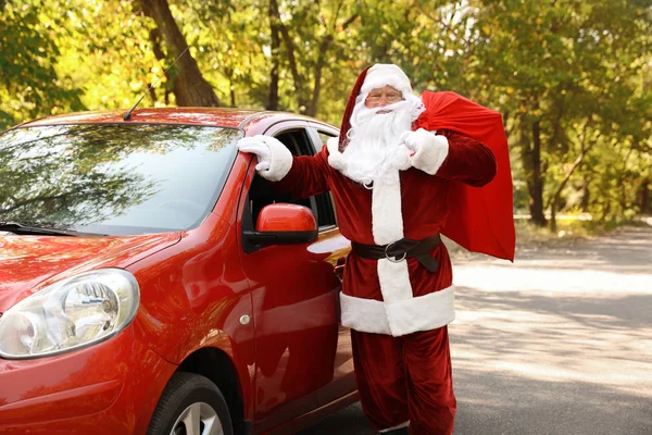 Autêntico Papai Noel com saco cheio de presentes perto do carro ao ar livre — Fotografia de Stock