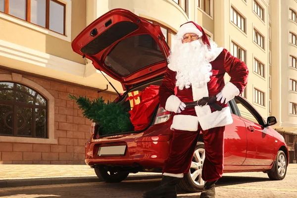 Autentico Babbo Natale vicino auto con abete e borsa piena di regali di Natale all'aperto, vista a basso angolo — Foto Stock