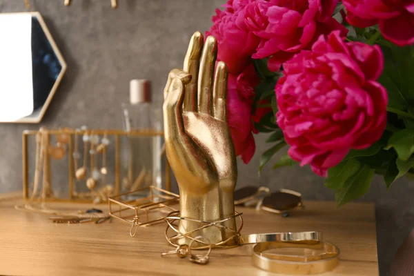 灰色の壁の近くのドレッシングテーブルに金のアクセサリーと花と組成物 — ストック写真