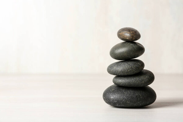 Stack of spa stones on table against white background, space for text