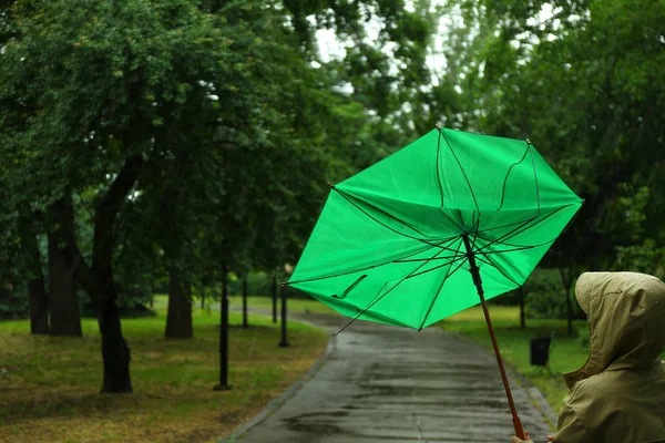 雨の日に公園で壊れた緑の傘を持つ女性 — ストック写真