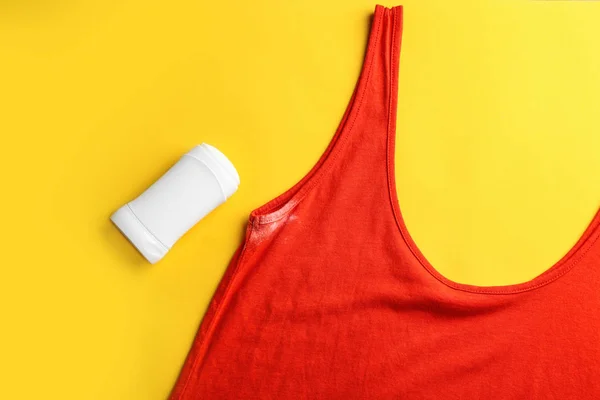 Clothes with stain and deodorant on yellow background, top view — Stock Photo, Image