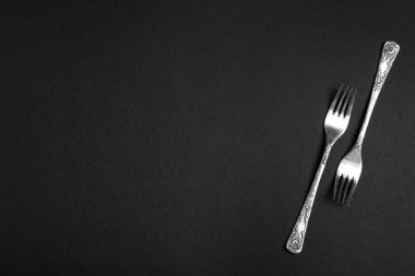 Siyah arka plan üzerinde gümüş çatallar, metin için boşluk ile düz yatıyordu