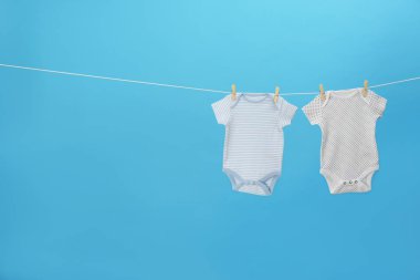 Renkli bebek onesies mavi arka plan, metin için alan karşı giysi hattı asılı. Çamaşır günü