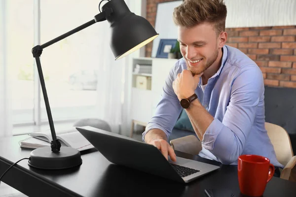 Junger Mann benutzt Laptop an Tisch im Haus — Stockfoto