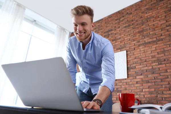 Junger Mann benutzt Laptop an Tisch im Haus — Stockfoto