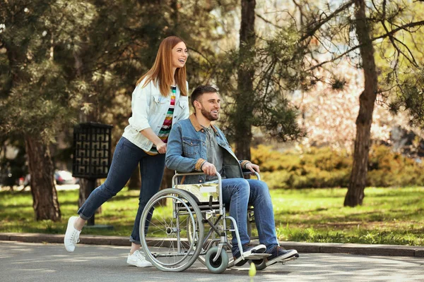 Молодий чоловік в інвалідному візку і радісна жінка в парку — стокове фото