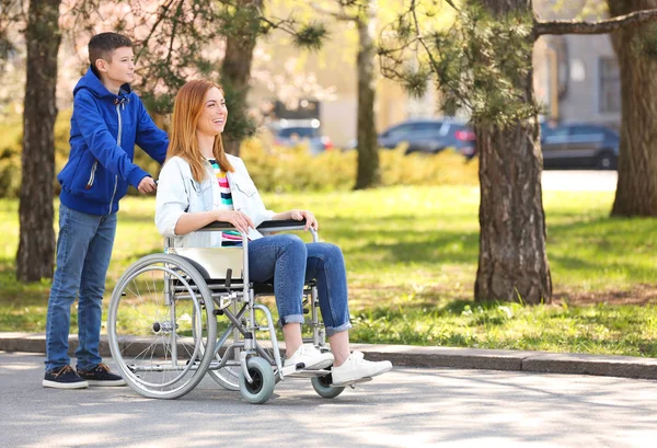 Donna in sedia a rotelle e suo figlio al parco nella giornata di sole — Foto Stock