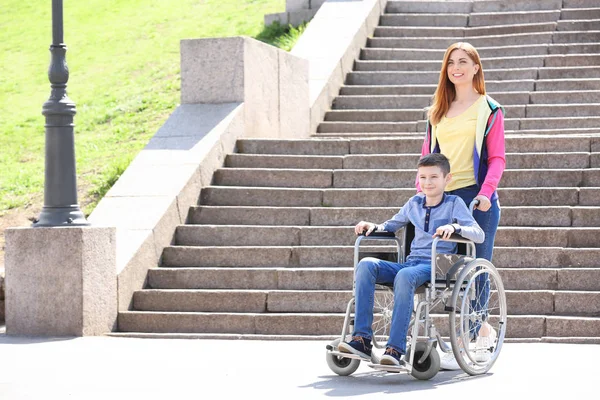 Niño preadolescente en silla de ruedas con su madre al aire libre — Foto de Stock