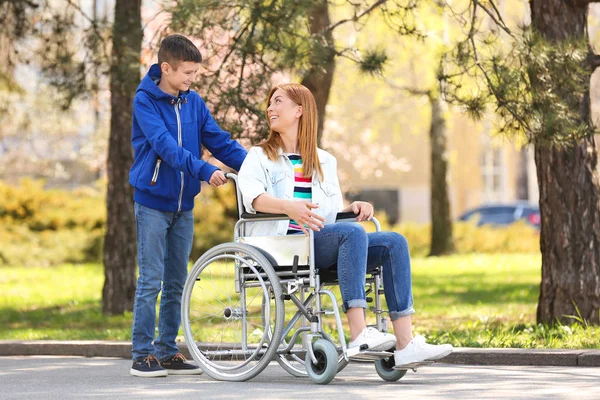 Женщина в инвалидном кресле и ее сын в парке в солнечный день — стоковое фото