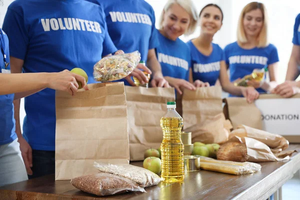 Команда волонтеров, собирающих пожертвования на еду за столом, крупным планом — стоковое фото
