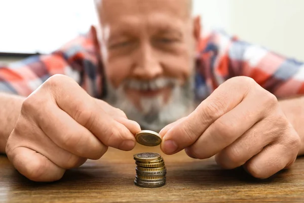 Senior man stacking up coins at table, focus on hand — Stock Photo, Image