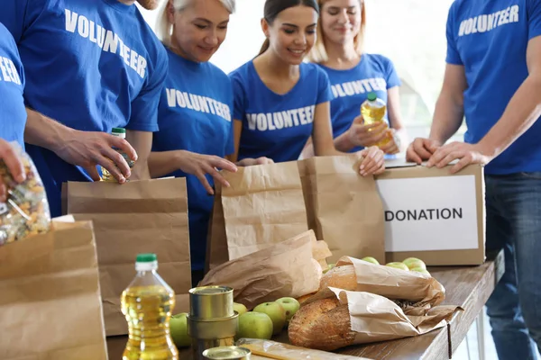 Команда волонтеров, собирающих пожертвования на еду за столом, крупным планом — стоковое фото