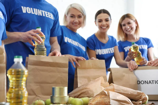 Team di volontari che raccolgono donazioni di cibo a tavola, primo piano — Foto Stock