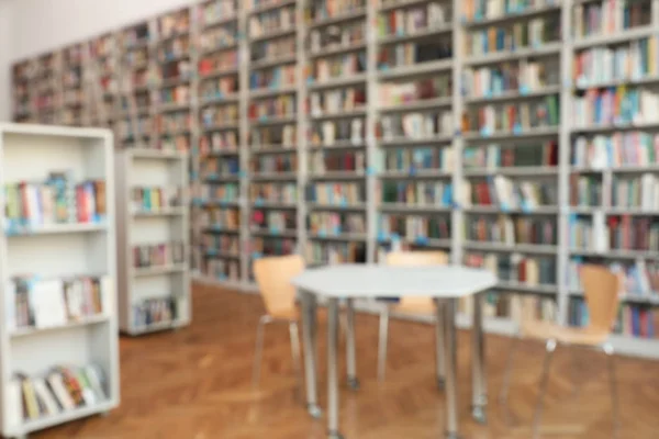 Verschwommener Blick auf Bücherregale und Tisch in der Bibliothek — Stockfoto