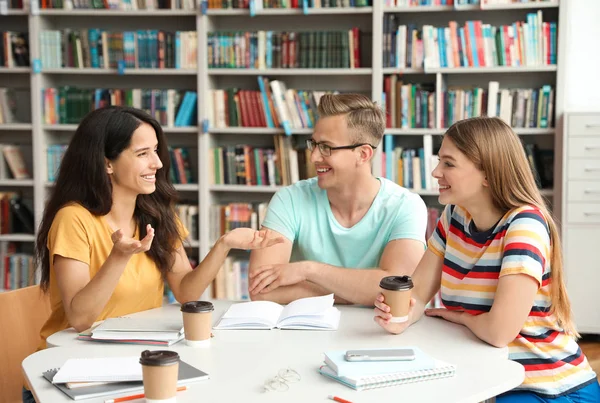 Jovens discutindo projeto de grupo à mesa na biblioteca — Fotografia de Stock