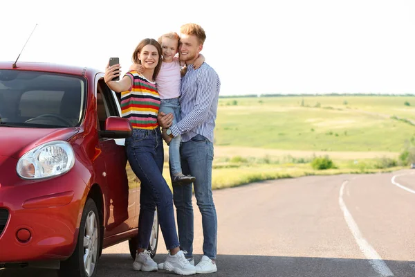 ロードトリップで車の近くで自分撮りを取る幸せな若い家族 — ストック写真