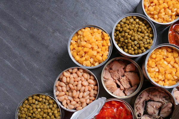 Latas abertas de produtos conservados em mesa cinza, flat lay com espaço para texto — Fotografia de Stock