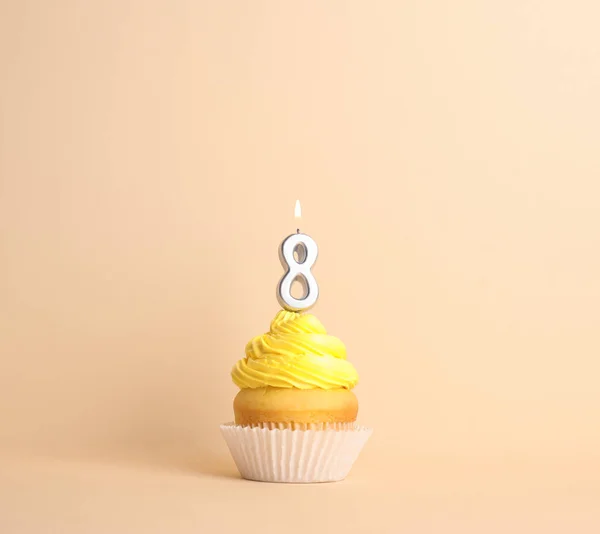 Cupcake d'anniversaire avec numéro huit bougie sur fond beige — Photo
