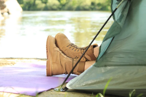 Jeune homme reposant dans une tente de camping au bord de la rivière, gros plan. Espace pour le texte — Photo