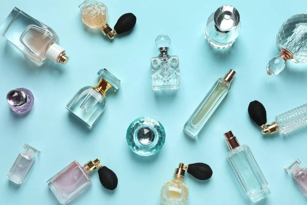 Composición plana con diferentes botellas de perfume sobre fondo azul claro — Foto de Stock