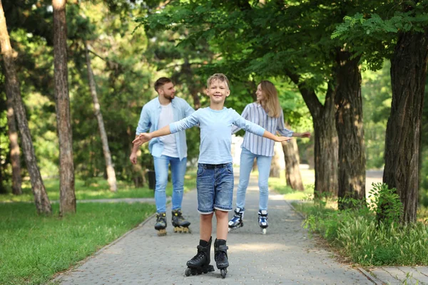 Giovane famiglia felice pattinaggio a rotelle nel parco estivo — Foto Stock